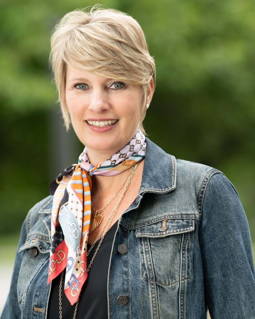 Professional headshot of a woman in a denim jacket and colorful scarf, illustrating high-quality headshot price